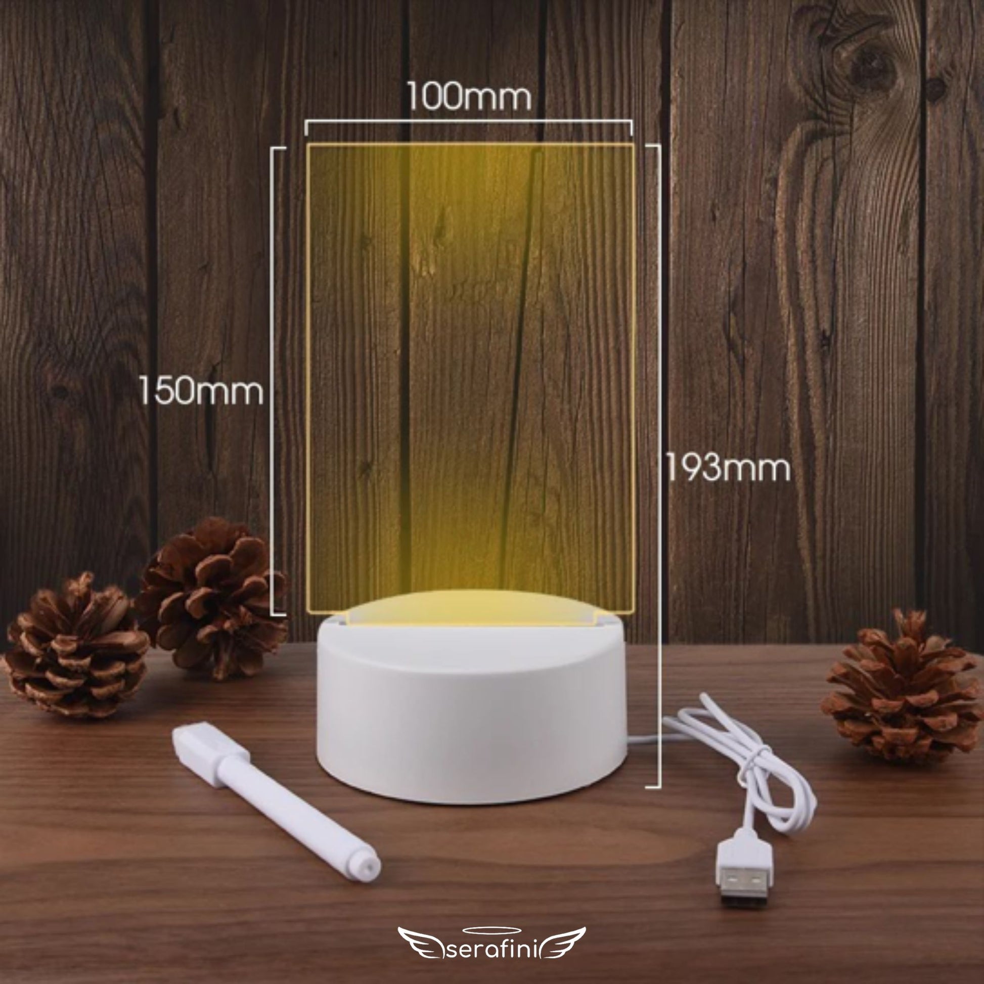 Foto mostrando medidas da Lousa Criativa em formato vertical: 150mm de altura por 100mm de largura o display de acrílico transparente. Altura total incluindo a base: 193mm. Na imagem aparece o cabo carregador e a caneta borracha.