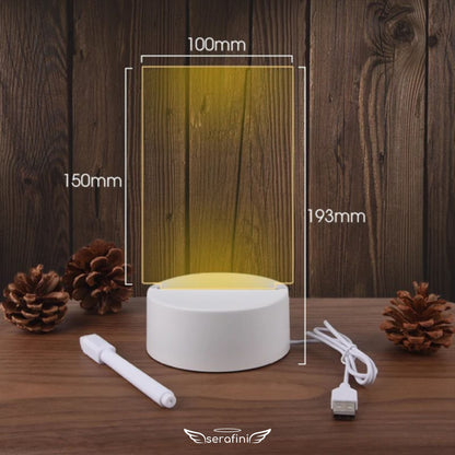 Foto mostrando medidas da Lousa Criativa em formato vertical: 150mm de altura por 100mm de largura o display de acrílico transparente. Altura total incluindo a base: 193mm. Na imagem aparece o cabo carregador e a caneta borracha.